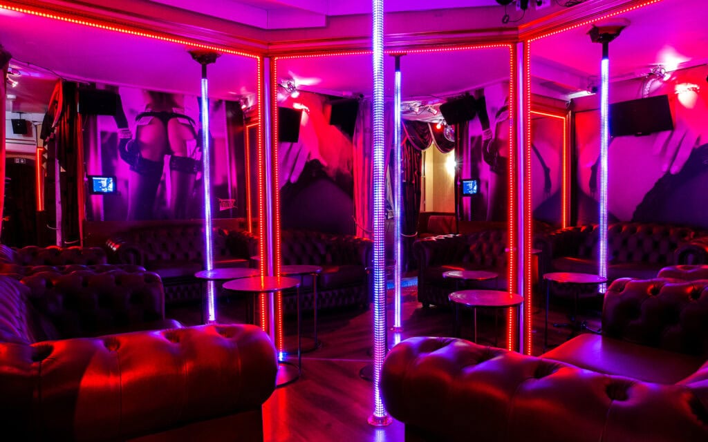 Room with several pole stages and Chesterfield sofas at String Showbar, Oslo
